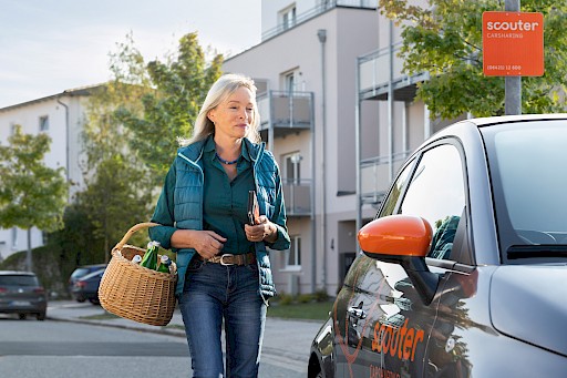 Frau mit Einkaufskorb und Carsharing Auto